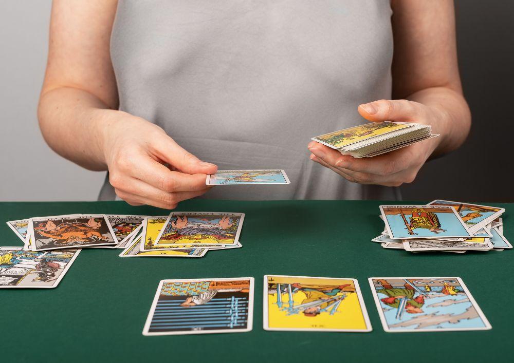 Persona experta echando las cartas del tarot a un cliente en una mesa verde para ver el futuro